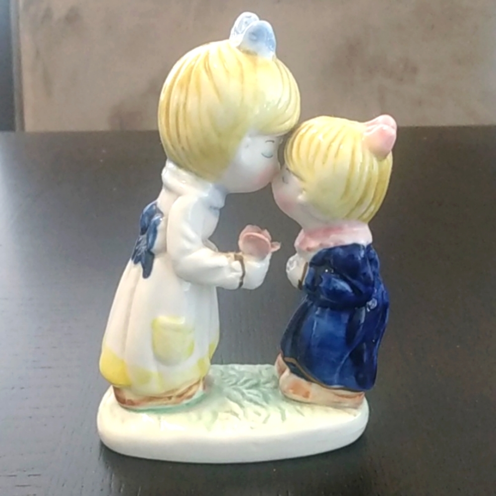 Sisterly love little girls best friends holding a flower nose kissing figurine